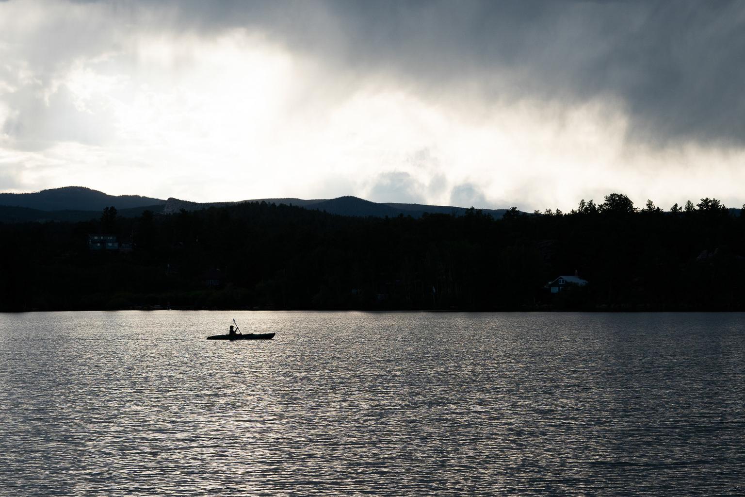 Red Feather Lakes kayaker on Hiawatha Lake as clouds roll in.