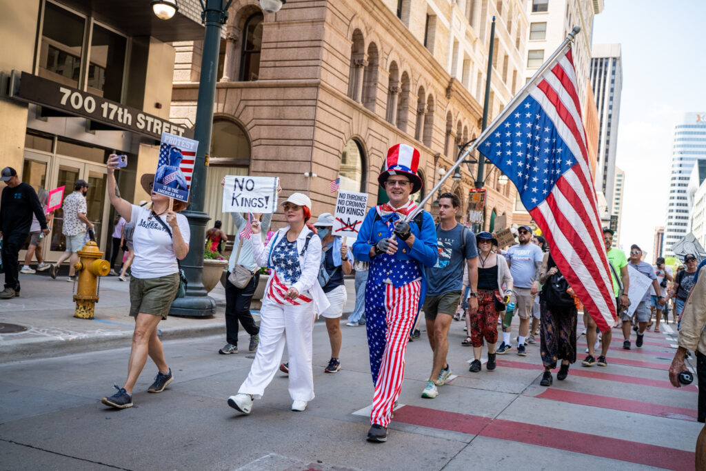 A group of people are walking down a street, some of them dressed in patriotic American attire.