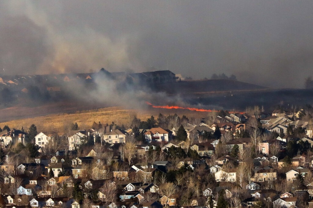 Marshall Fire flames and smoke rise in grassland between neighborhoods in Superior,