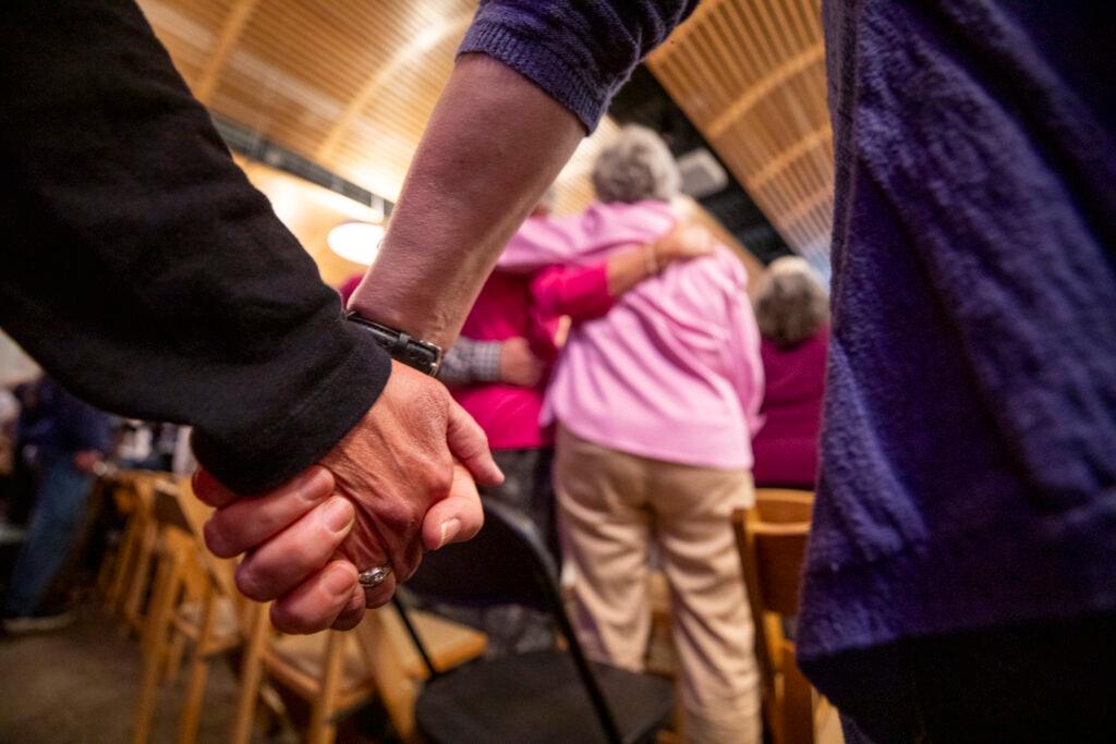 A group of people are gathered together, with some of them holding hands. They are standing close to each other.
