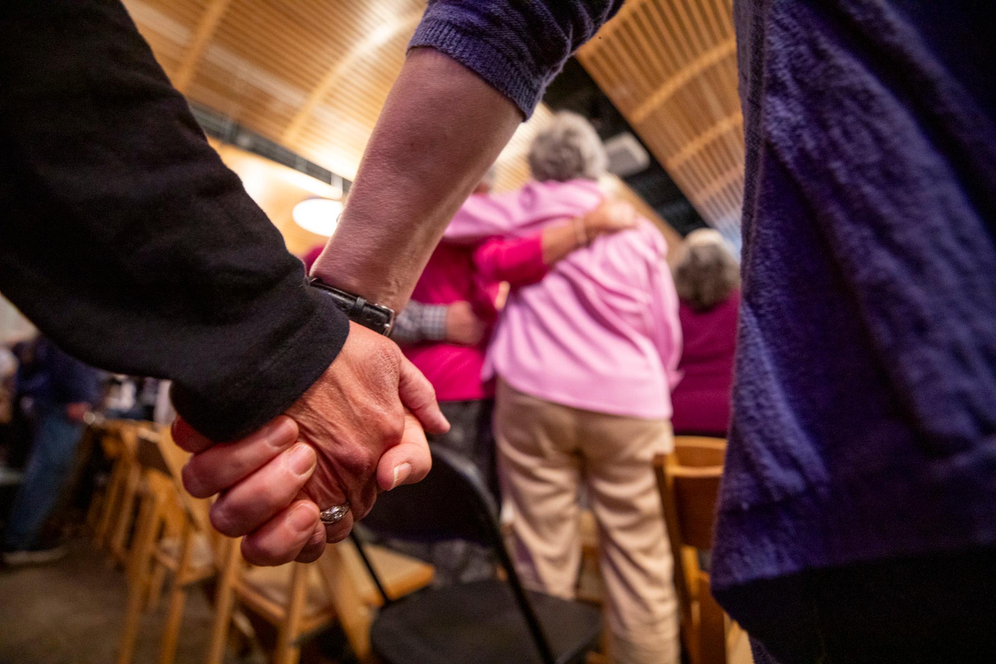 A group of people are gathered together, with some of them holding hands. They are standing close to each other.