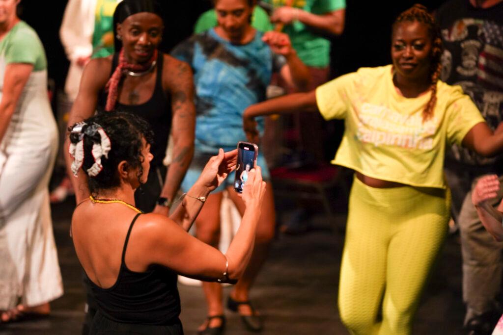 A dancer is filming other dancers as they warm up their bodies before the show.