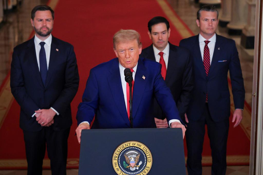 Man stands at podium flanked by three other men