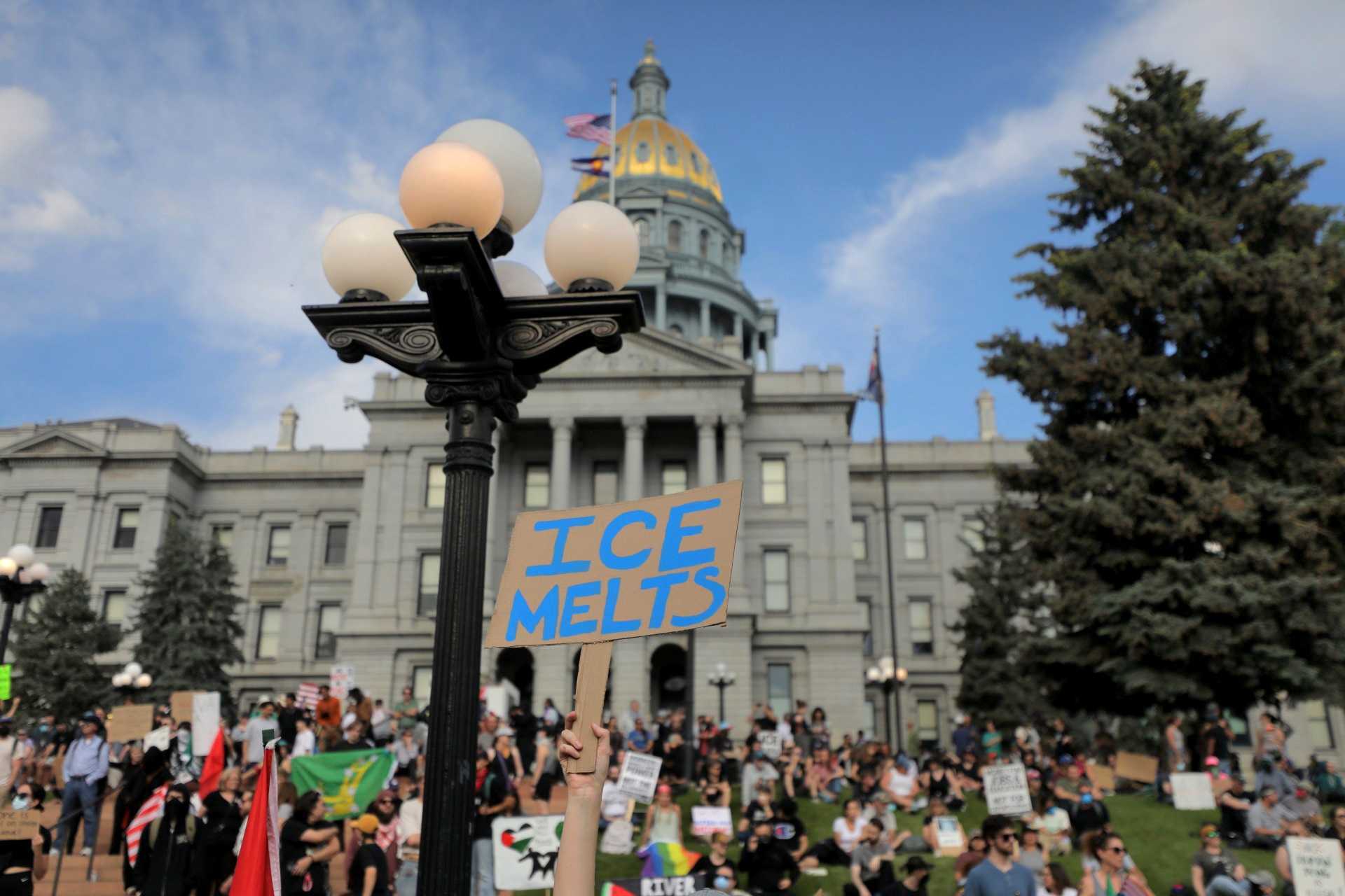 protest sign in front of state capitol says ICE melts in blue ink.