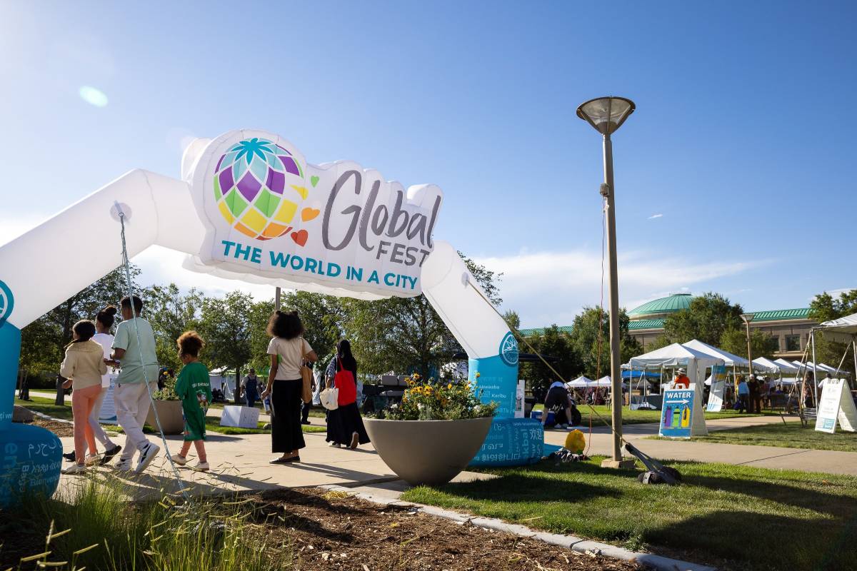 A large balloon archway with people walking through it in front of a large municipal building in the background