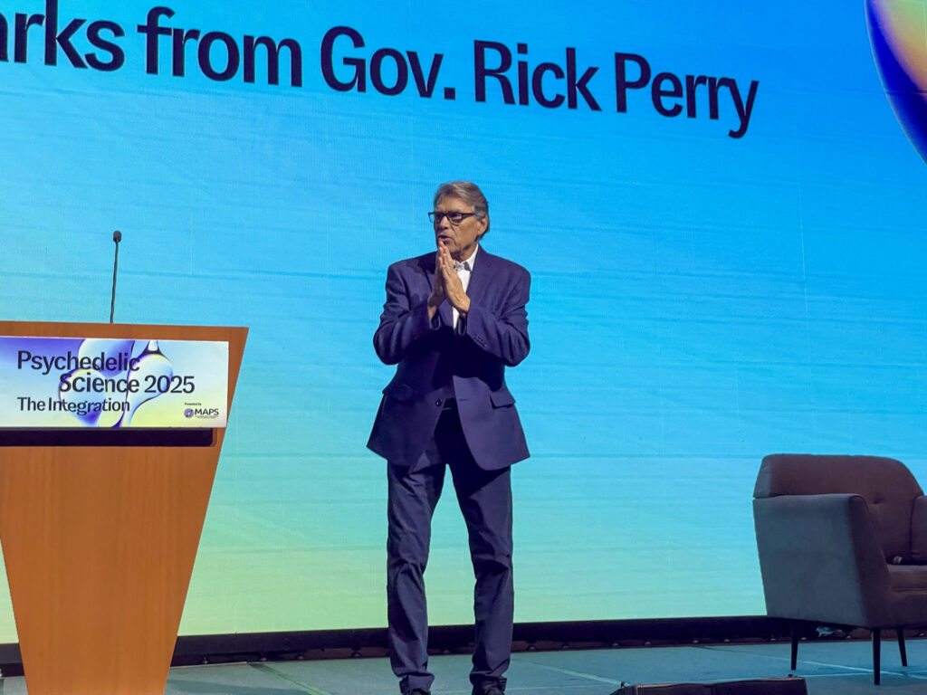 Texas man stands on stage in suit and glasses