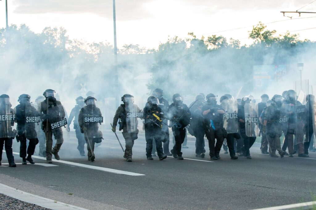 Law enforcement in riot gear move through a cloud of smoke toward protestors