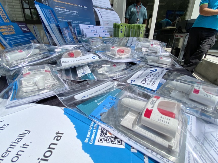 An array of packaged naloxone for use in preventing overdoses is displayed on a table outside