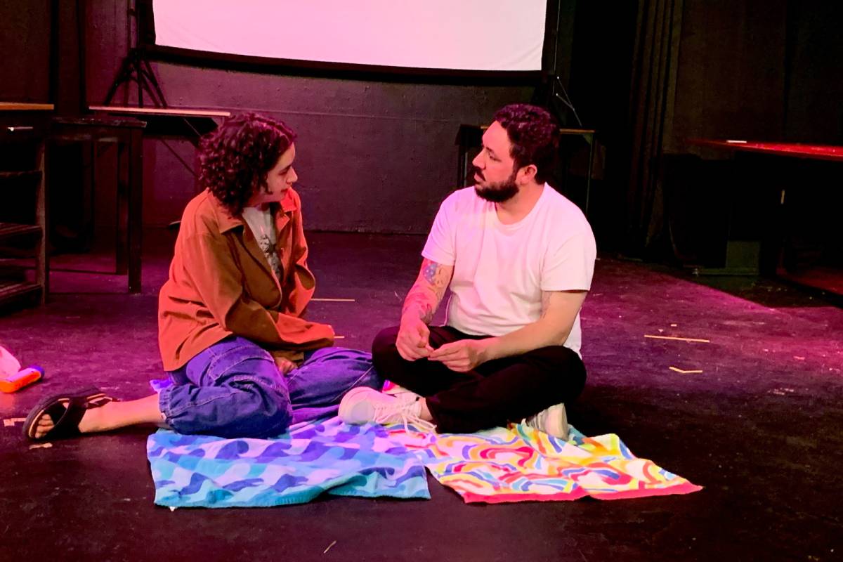 Two people dressed casually sitting in front of cloths on a stage