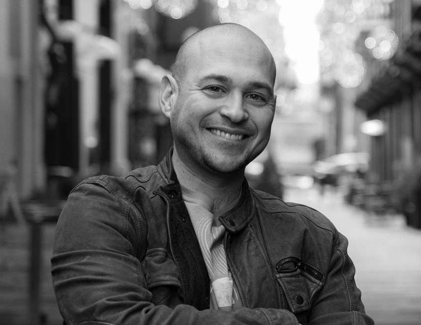 smiling man standing outside with arms crossed at chest