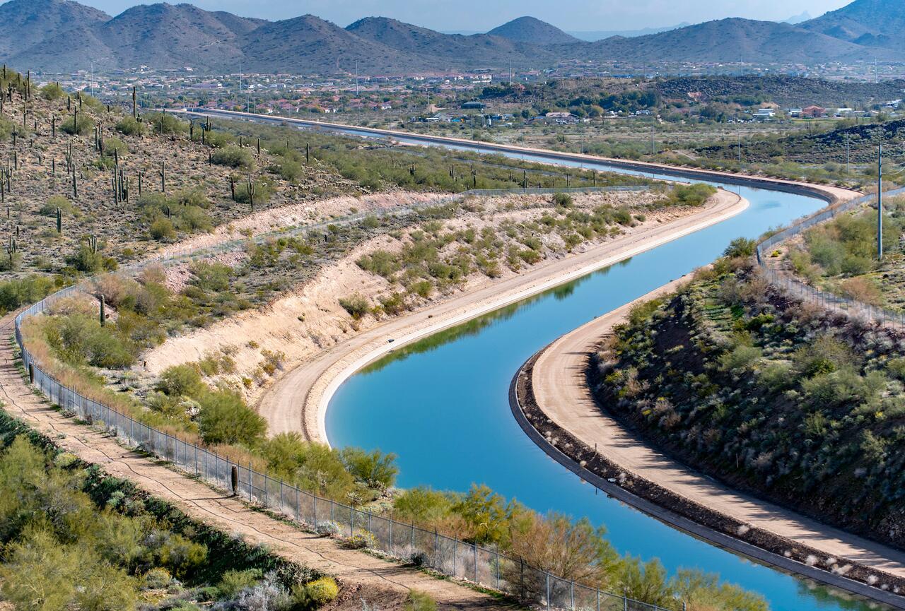 A canal carrying blue water flows through a desert landscape