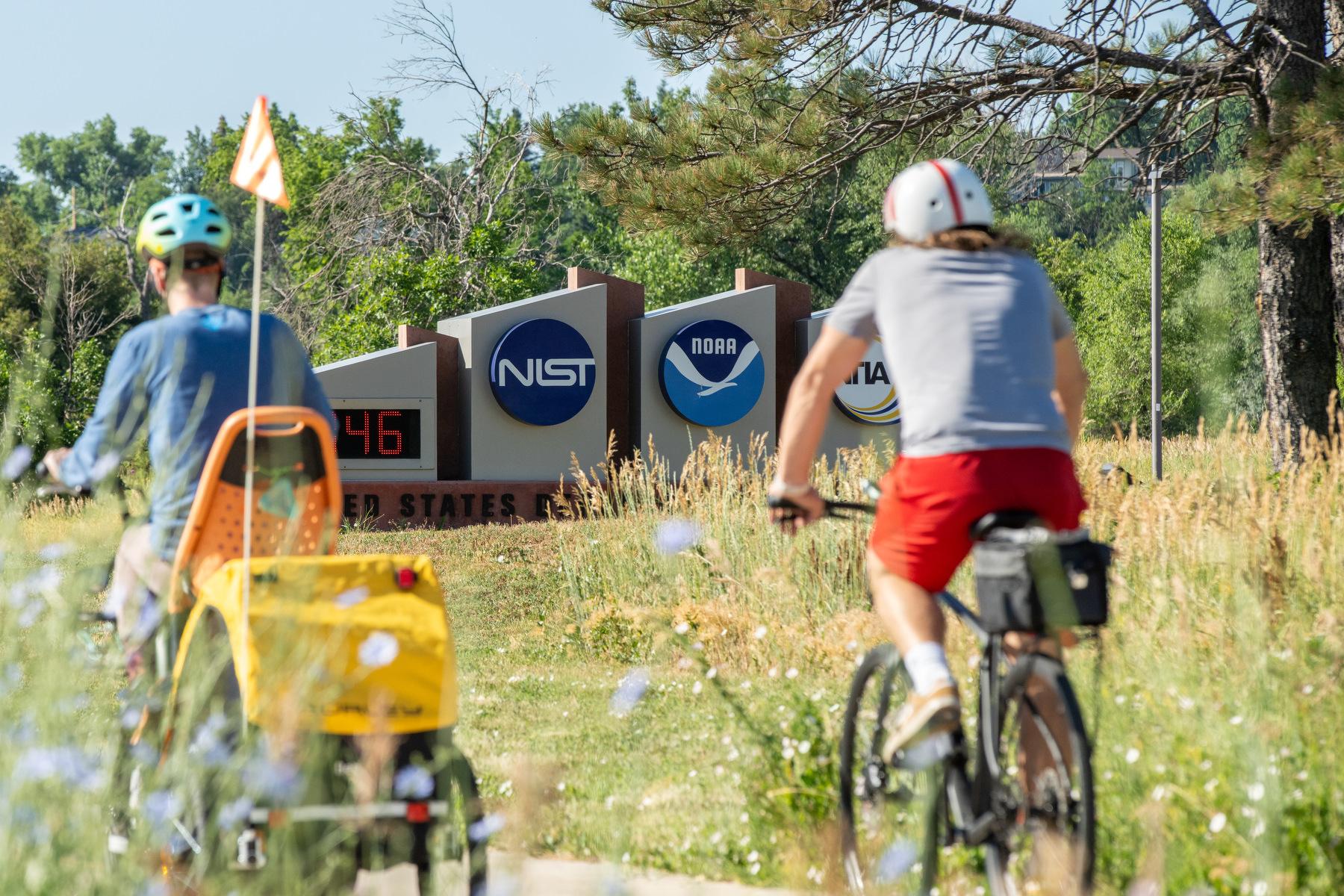 Bicycle riders pass by the entrance to the NOAA campus