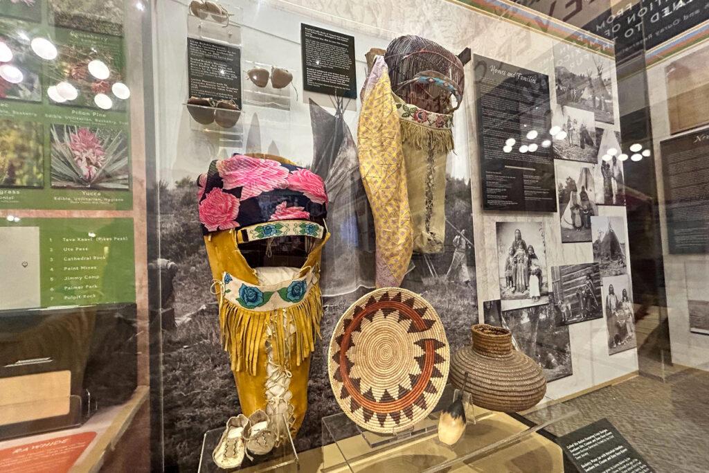 Photo shows two baby carriers, two basked and moccasins on display at an exhibit at the Pioneers Museum in Colorado Springs elevating Ute culture and history.