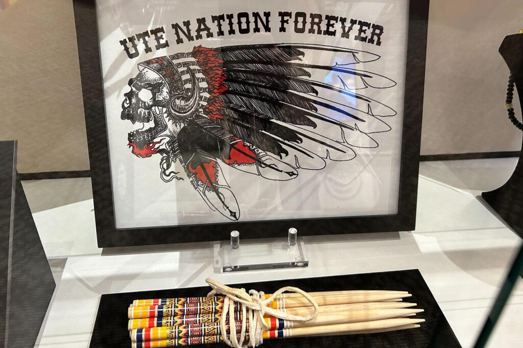 Photo shows a framed photo with a skull wearing a headdress with the saying "Ute Nation Forever" on display at the Pioneers Museum in Colorado Springs elevating Ute culture and history.