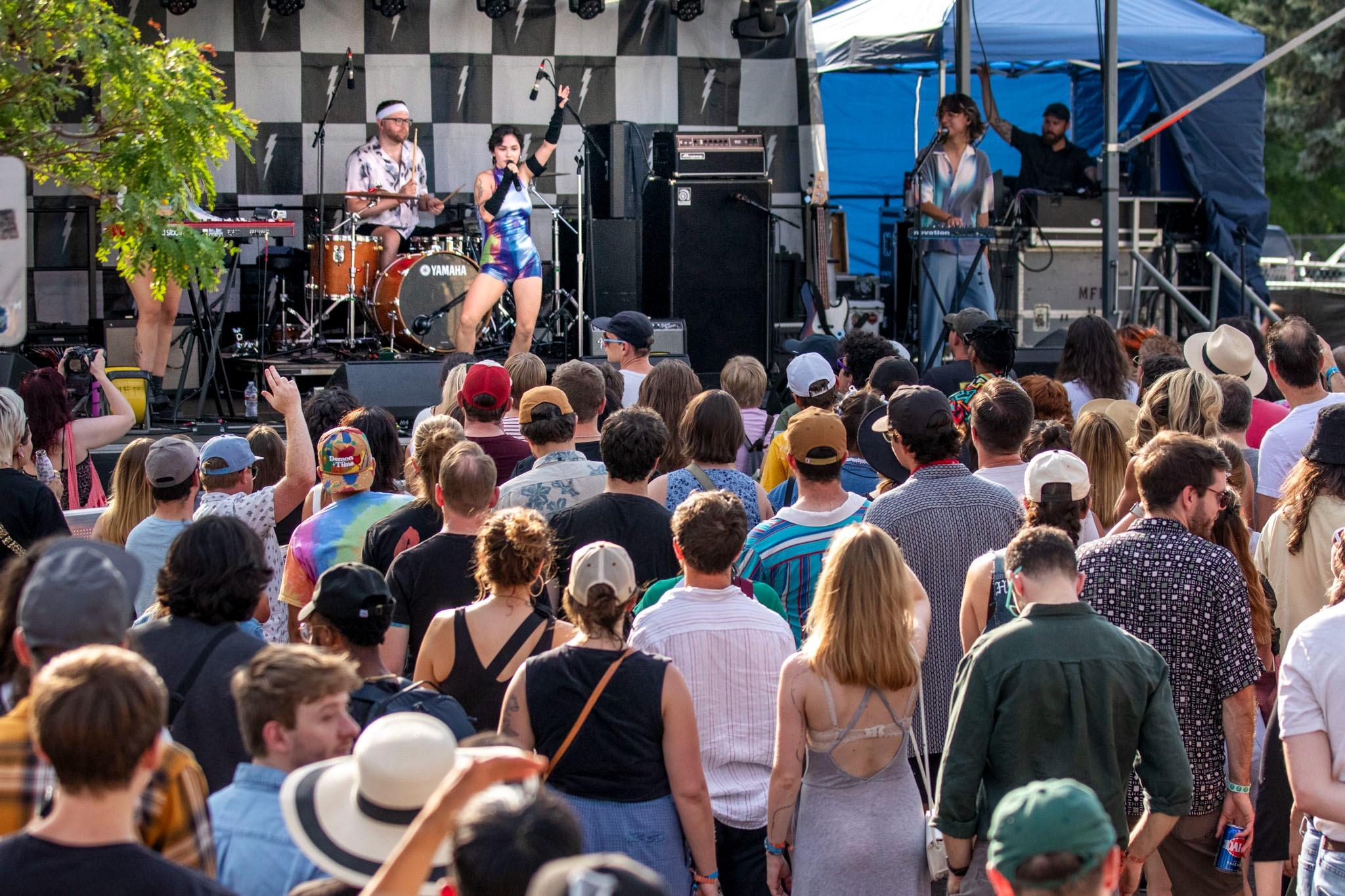 A crowd of people watch musicians on a stage