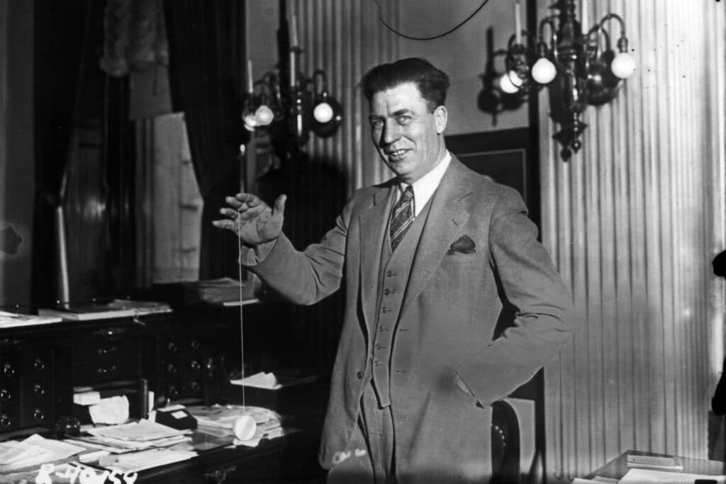 A black and white photograph of the governor playing with a yo-yo in his office