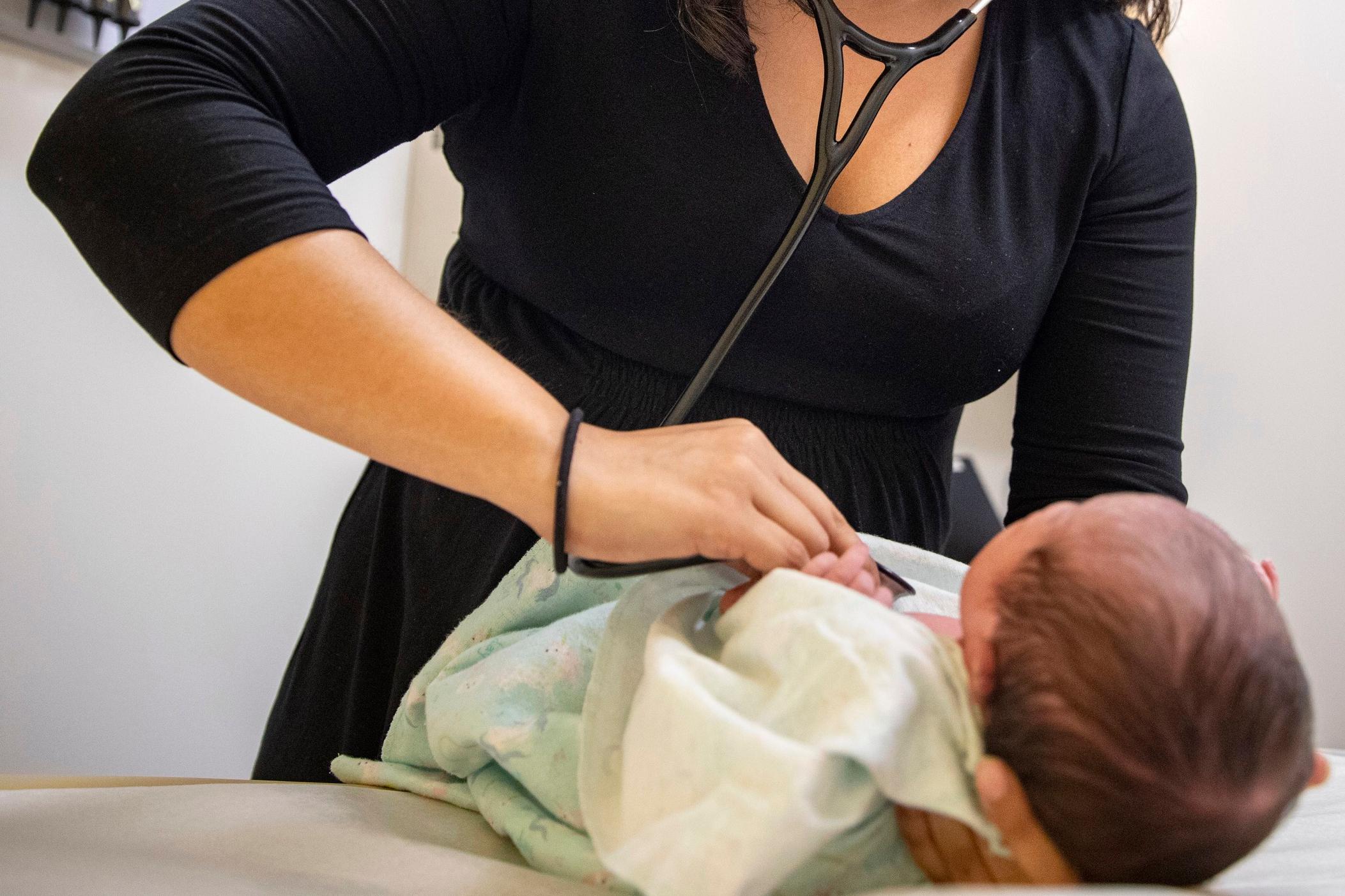 A person using a stethoscope on a baby