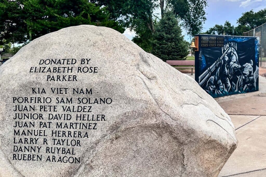 a large boulder with names carved in it and a mural in the background