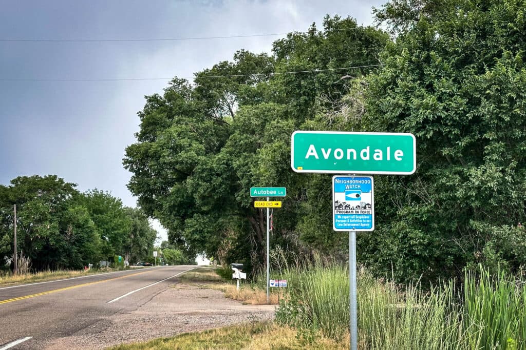 a green sign with while lettering along side a paved road