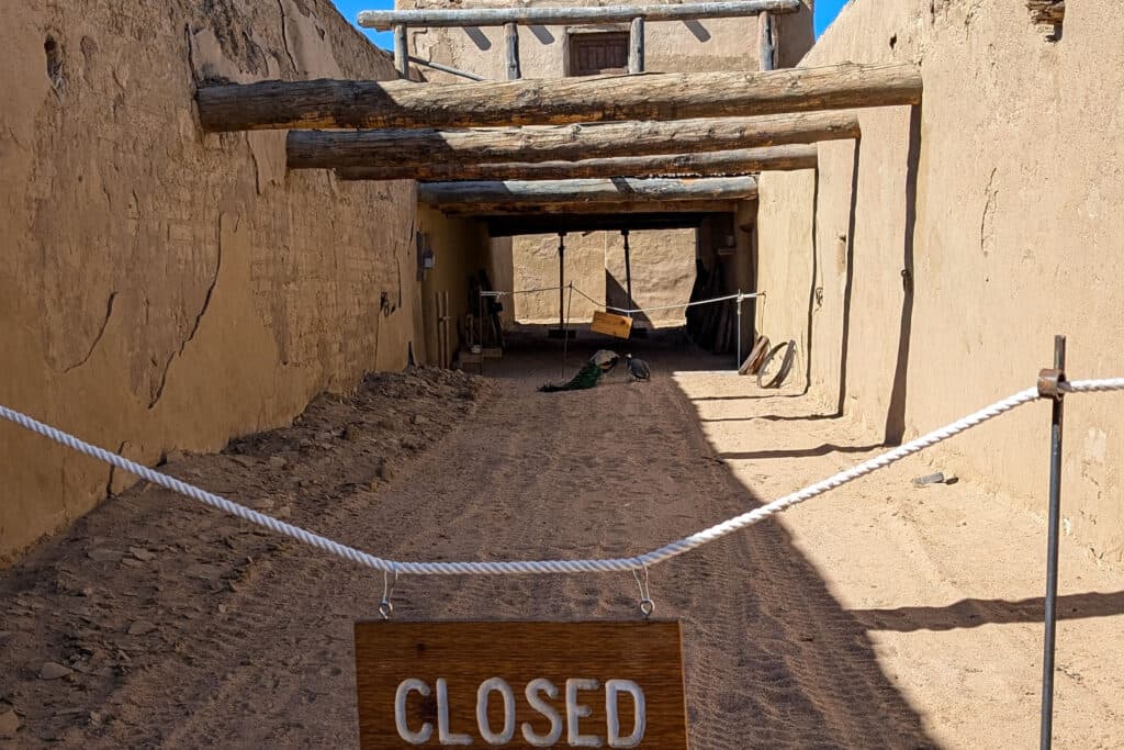 Roped off area with a closed sign inside the adobe structure