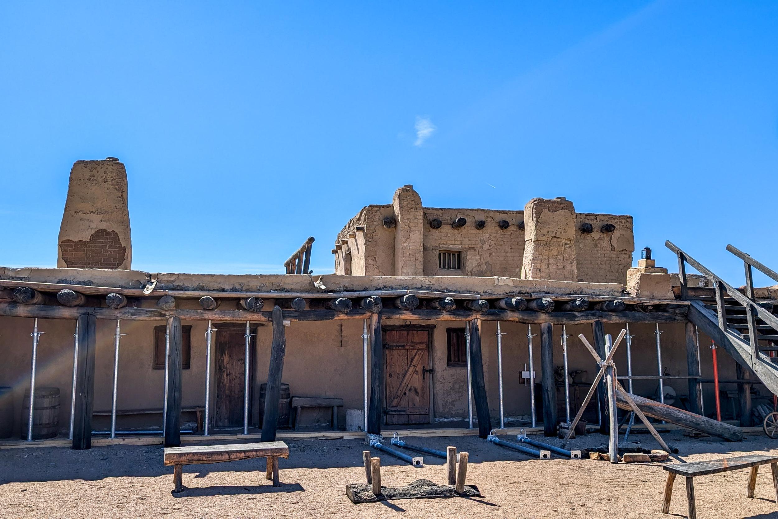 temporary metal jacks support the beams and covered porch on an adobe building