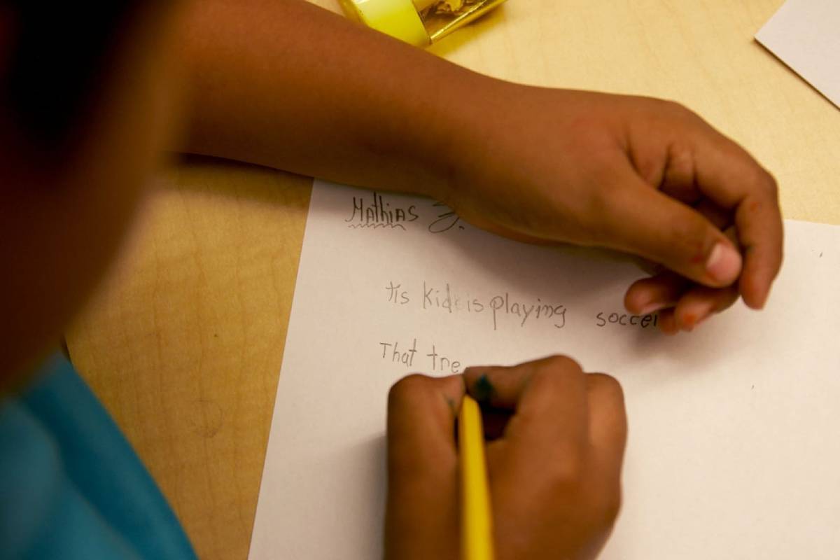 A child holding a pencil only their arms and hands are visible