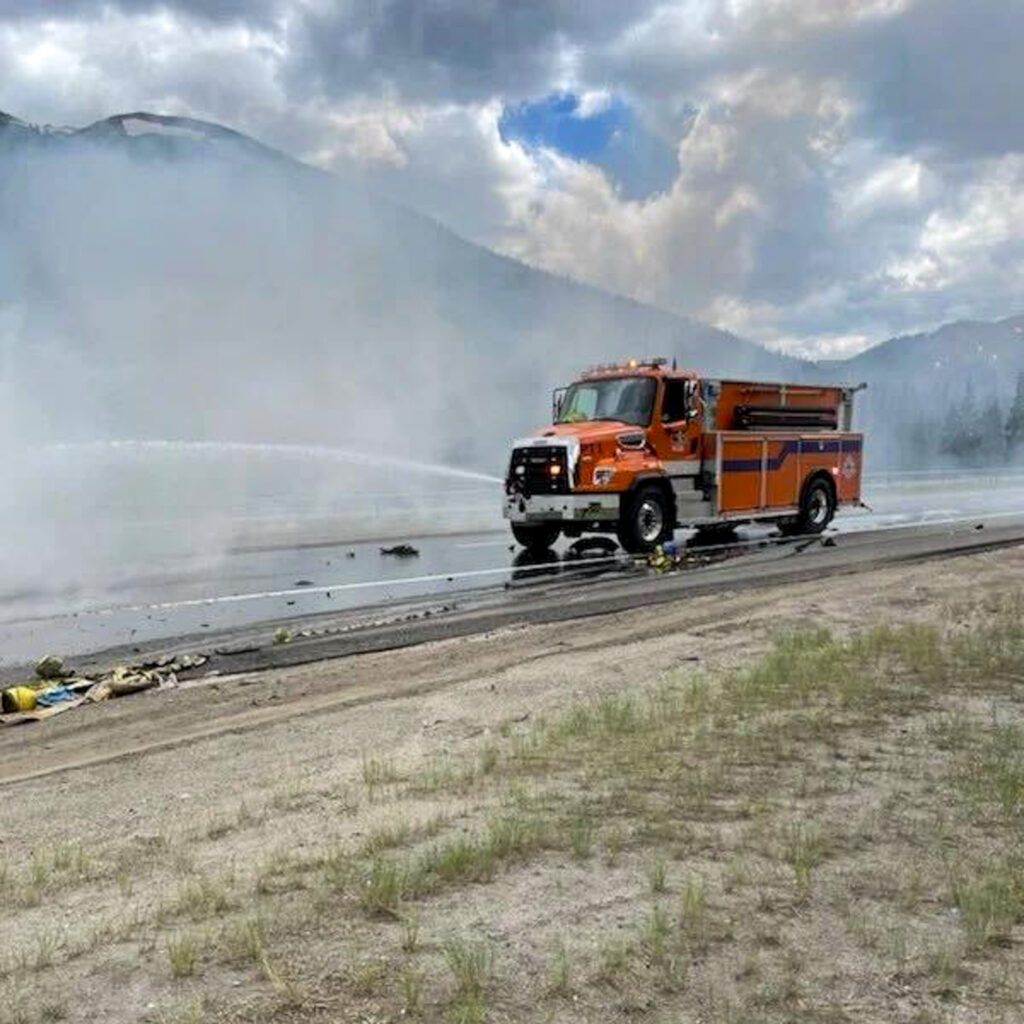An orange truck on the road surrounded by smoke and debris