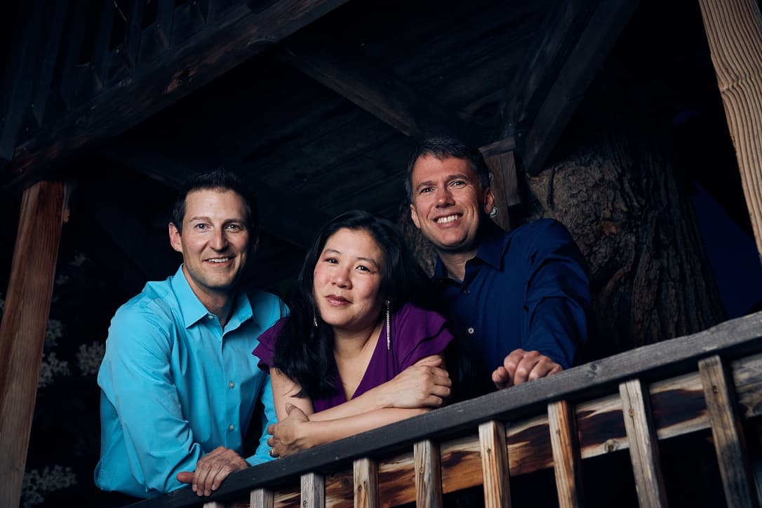 Two men and a woman leaning on a stair railing.