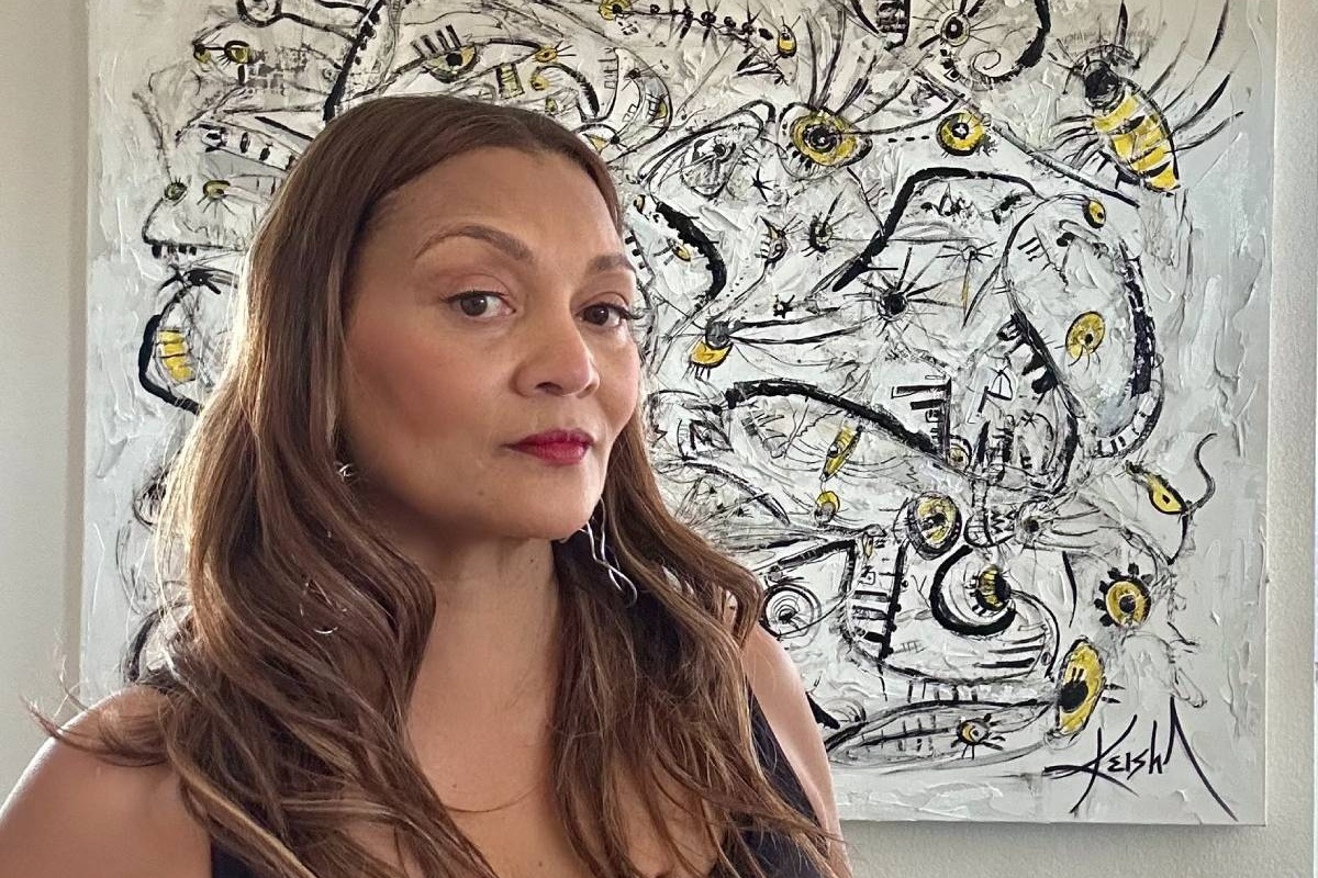Black woman wearing black body suit standing in front of large piece of artwork