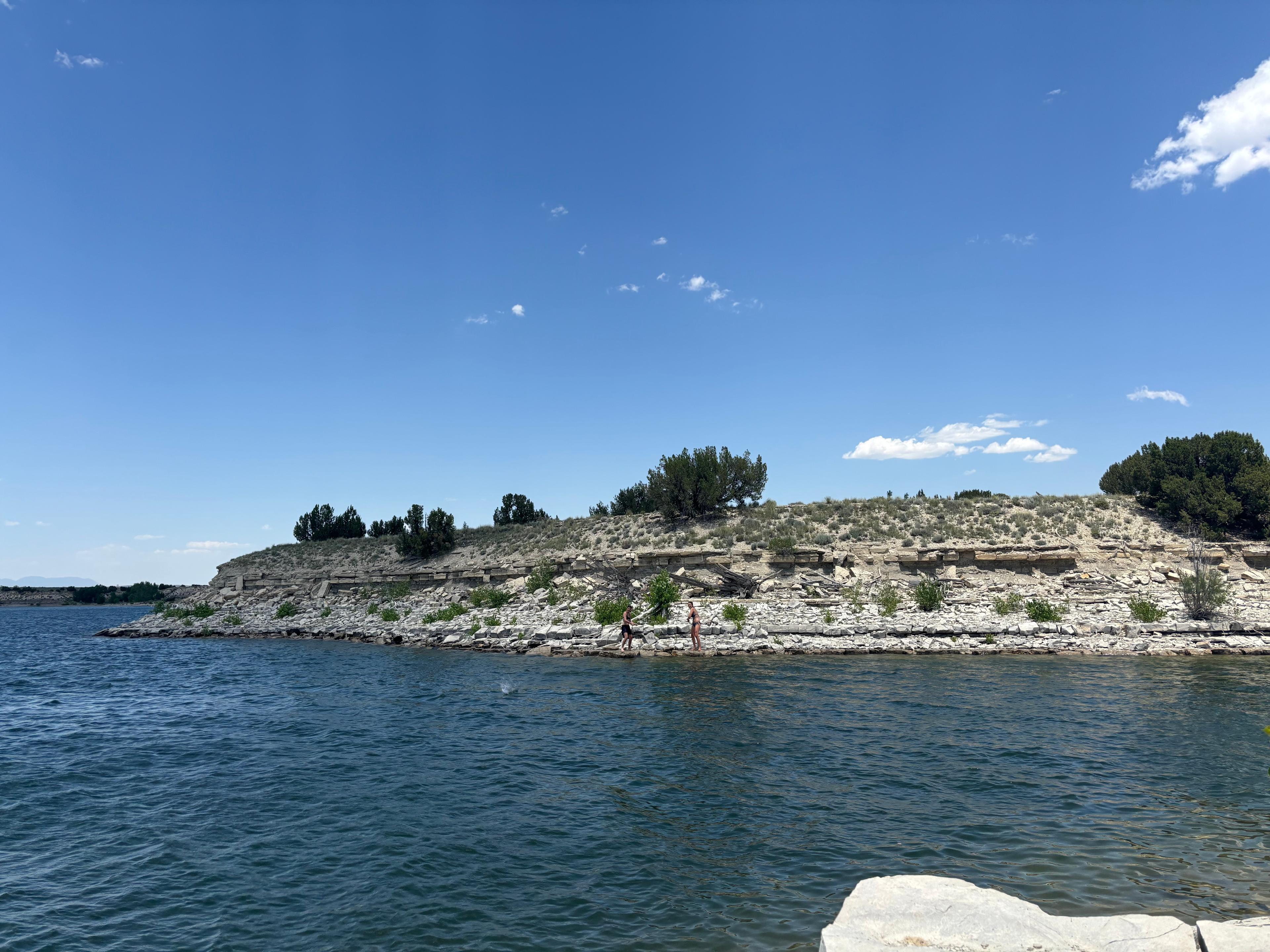 Two people skipping rocks across the water at Lake Pueblo.