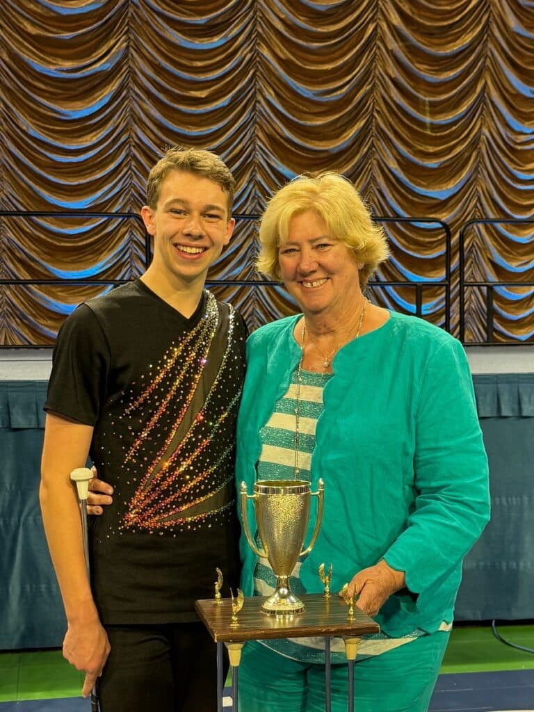 Two people stand next to trophy
