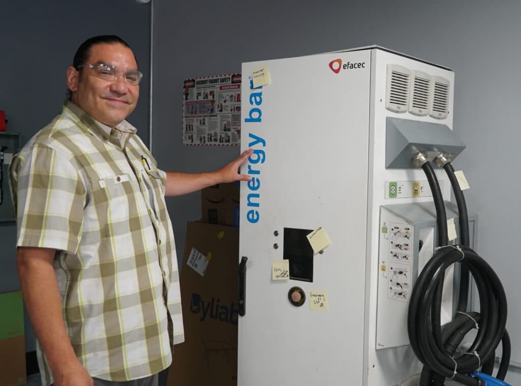 Trainee poses with EV charging station