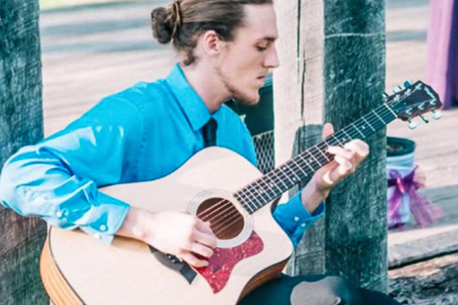 Daniel Foard in a blue shirt playing a guitar