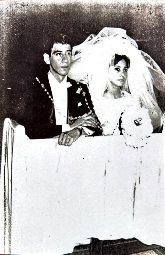 Black-and-white photo of the bride and groom seated together at the altar, with Evangelina wearing a long veil and Miguel in a suit.
