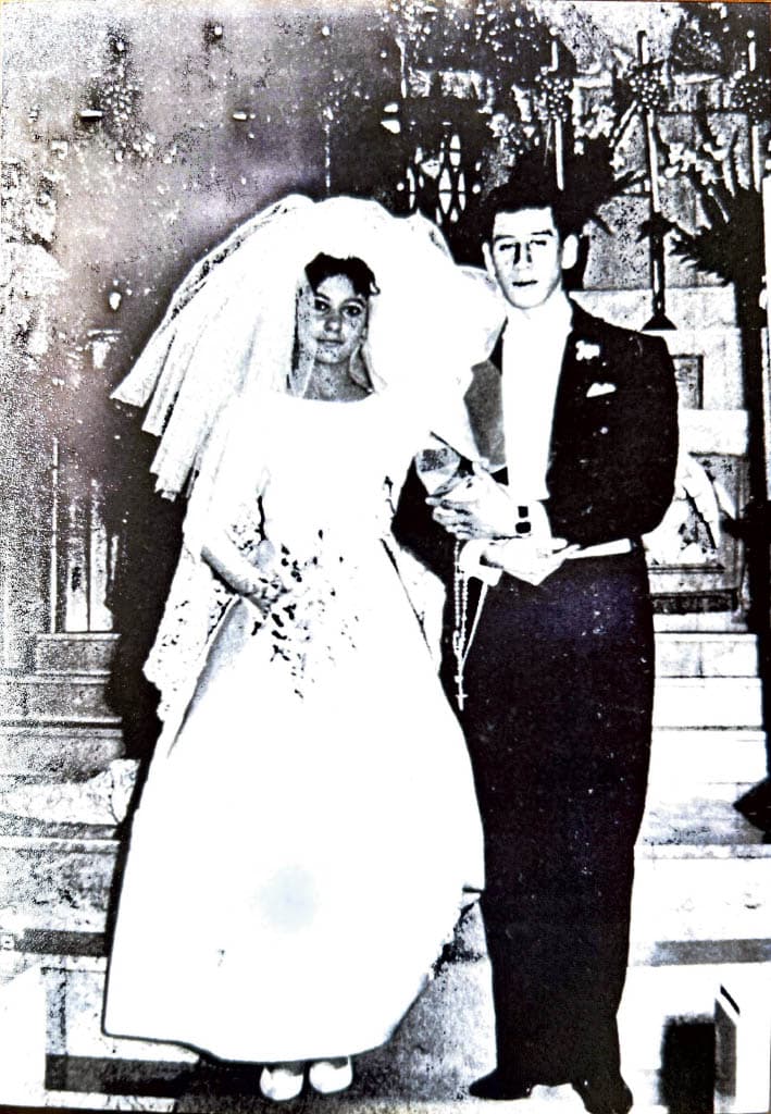 Black-and-white photo of the bride and groom standing together at the altar, with Evangelina in a lace gown and veil holding a bouquet.