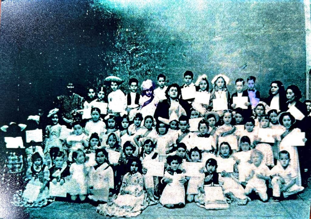 Group photo of dozens of children and adults dressed formally, gathered together.