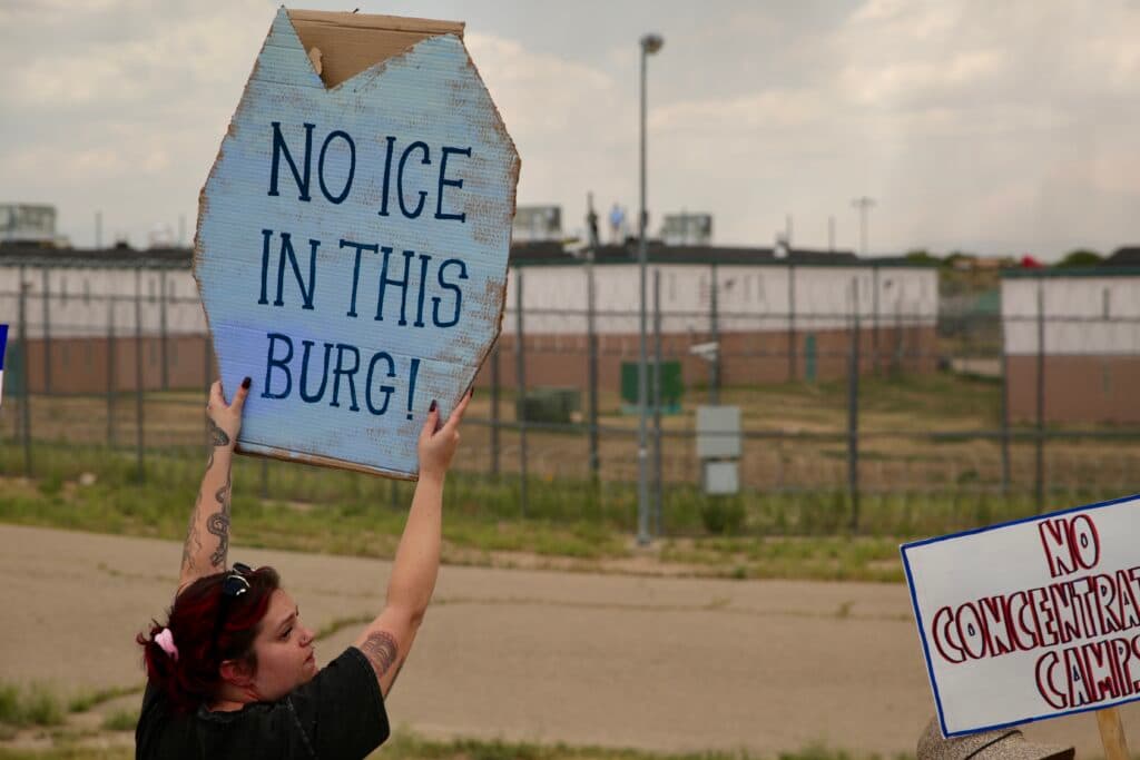 A woman holds a protest sign outside a Huerfano County detention facility.
