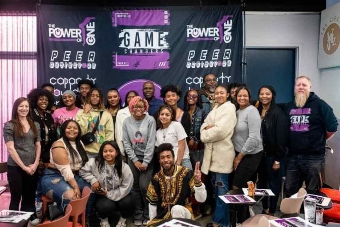 a group of people gather in front of a black white and purple banner