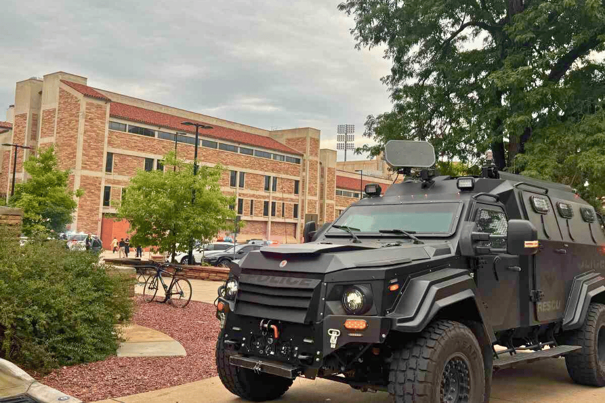 An armored police vehicle in front of red brick buildings