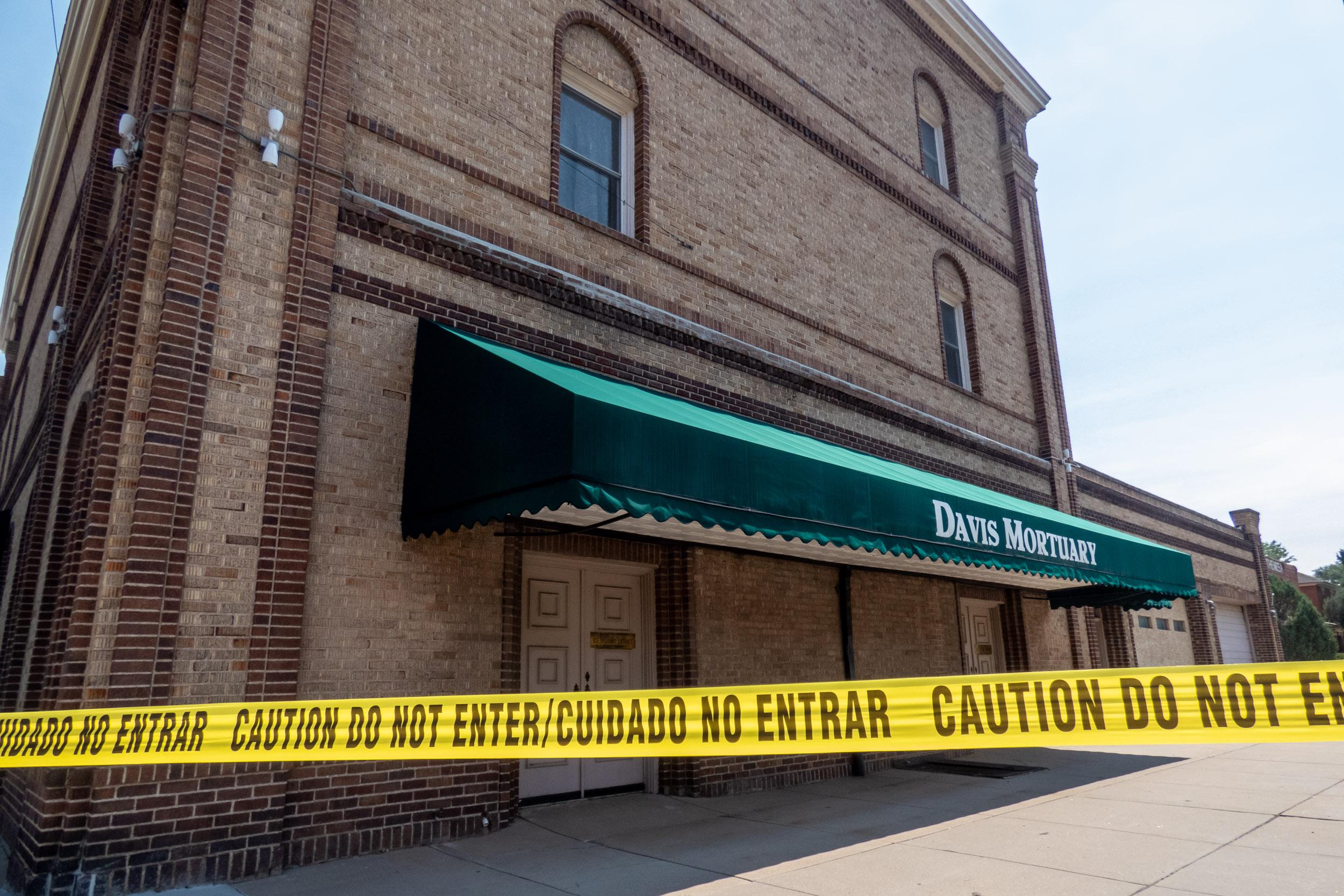 three story brick building with green awning surrounded by police tape