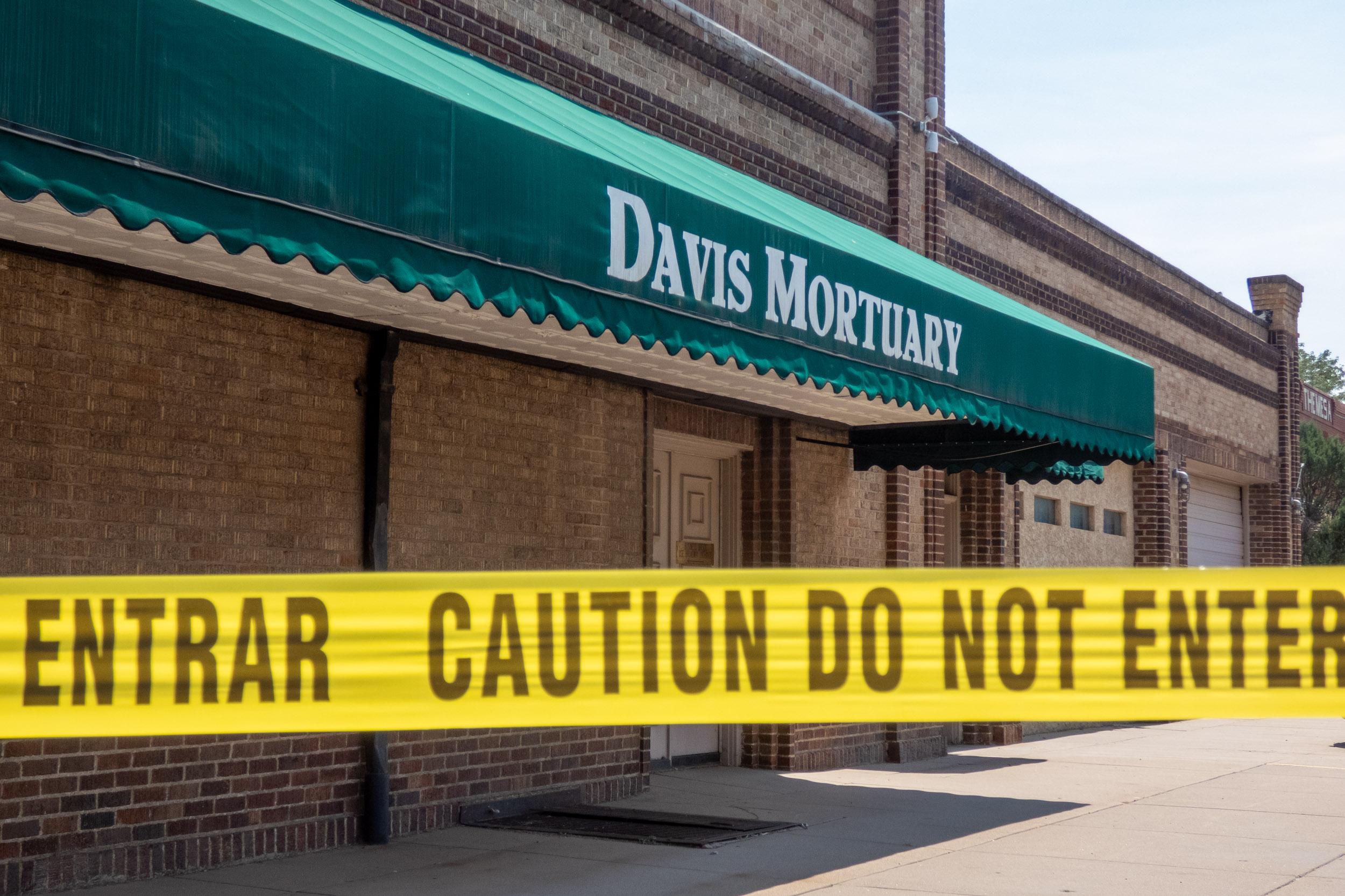 three story brick building with green awning surrounded by police tape
