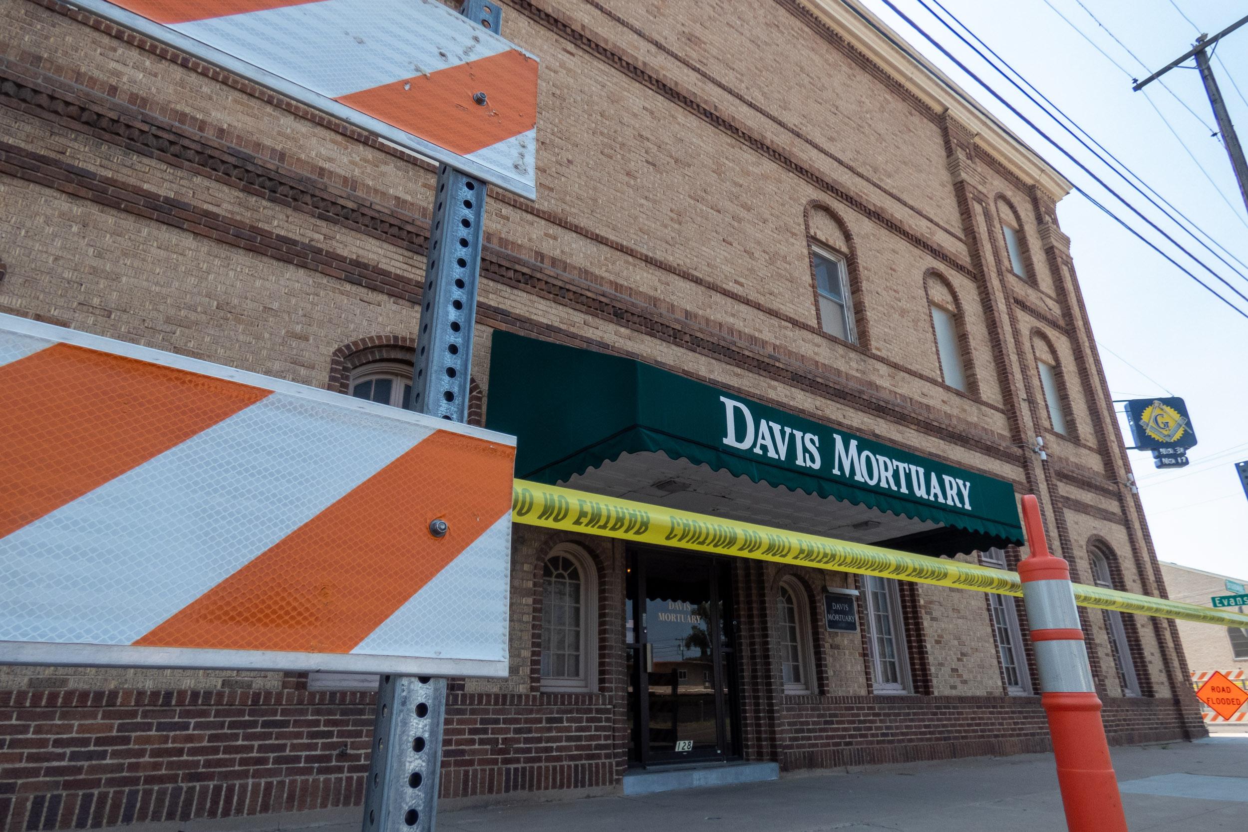 three story brick building with green awning surrounded by police tape and barriers
