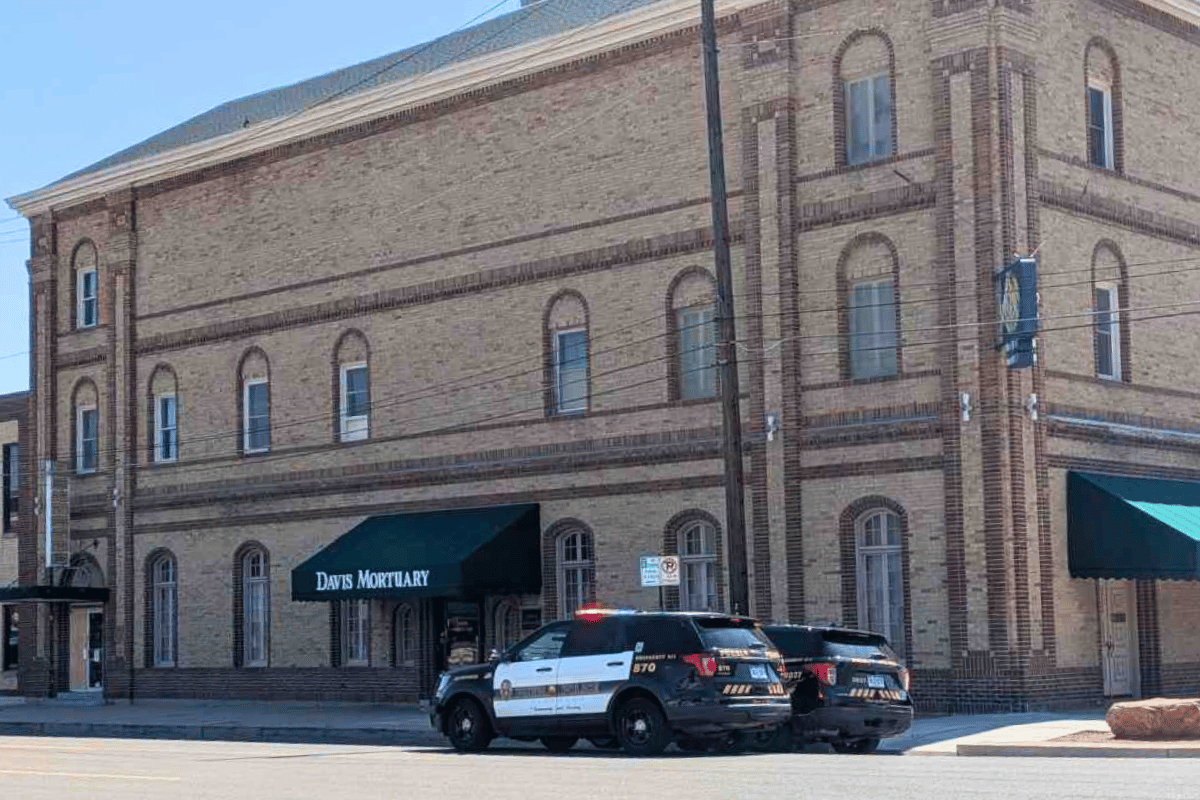 A brick building with two cop cars parked in front