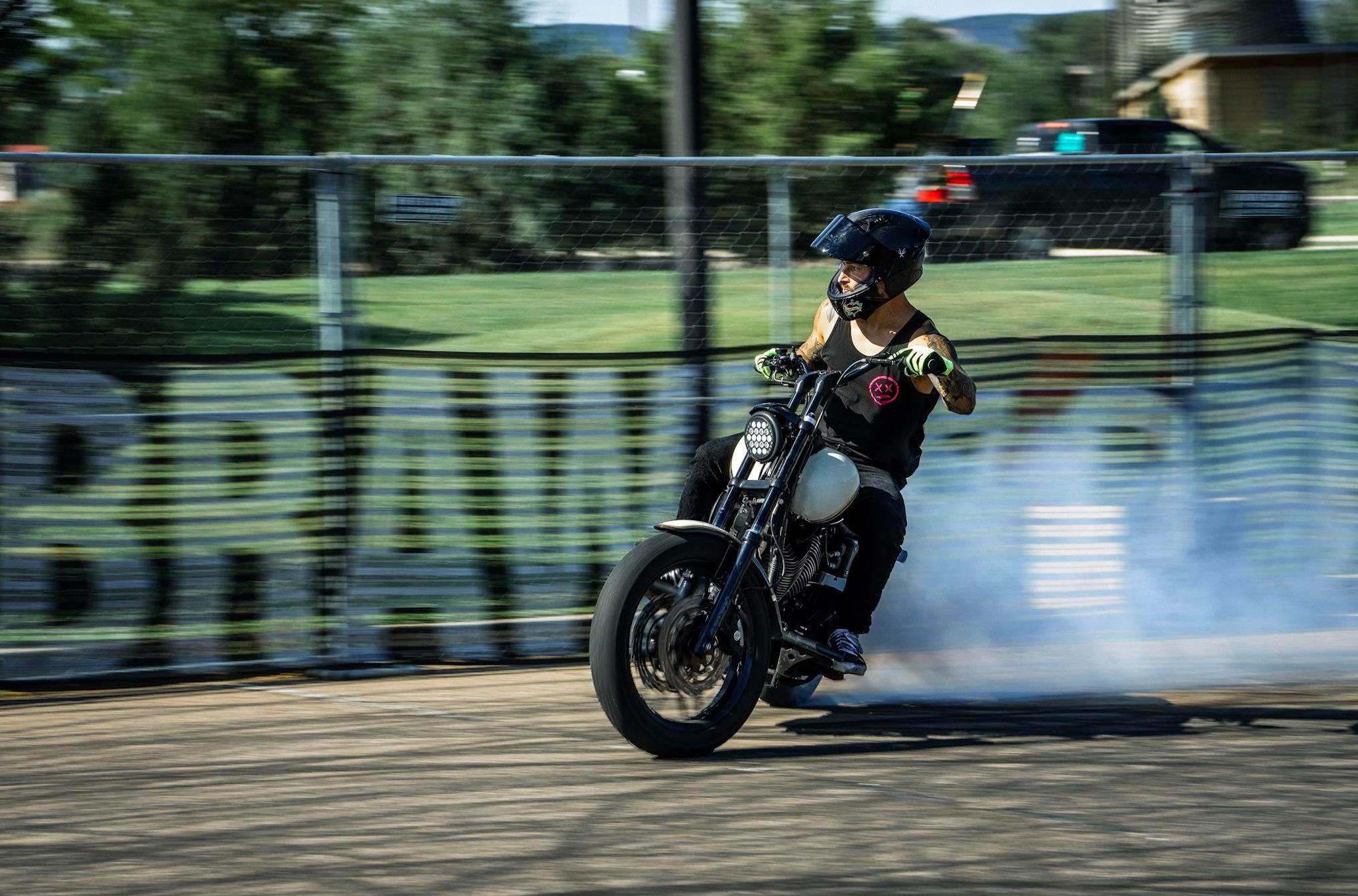A man on a motorcycle slides skillfully, leaving a streak of burning rubber behind him.