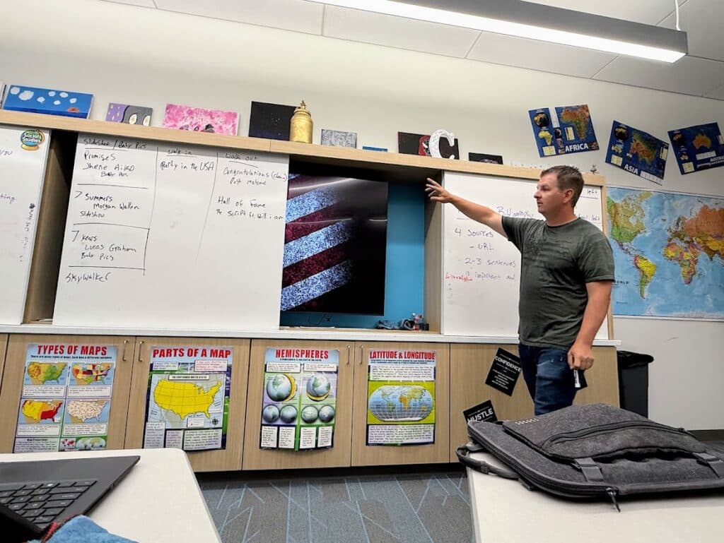 A teacher points to the white board.