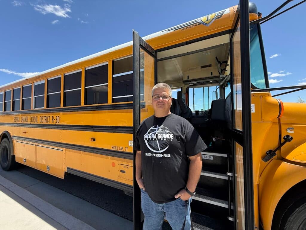 A man stands next to a bus.
