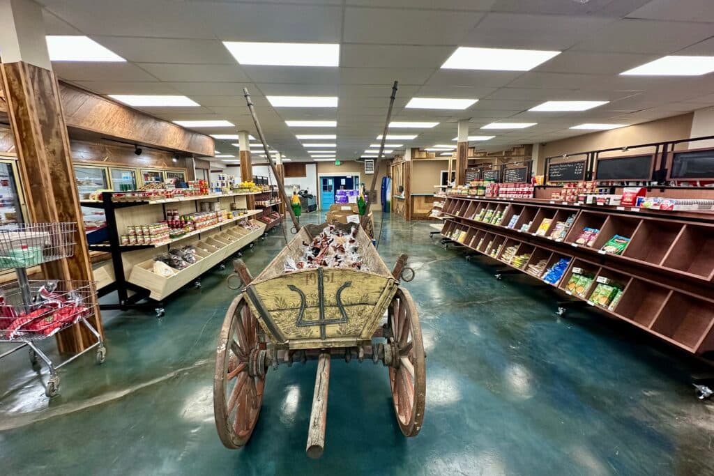 A wooden donkey cart filled with bags of potatoes is seen inside a small grocery store amidst other aisles of food.