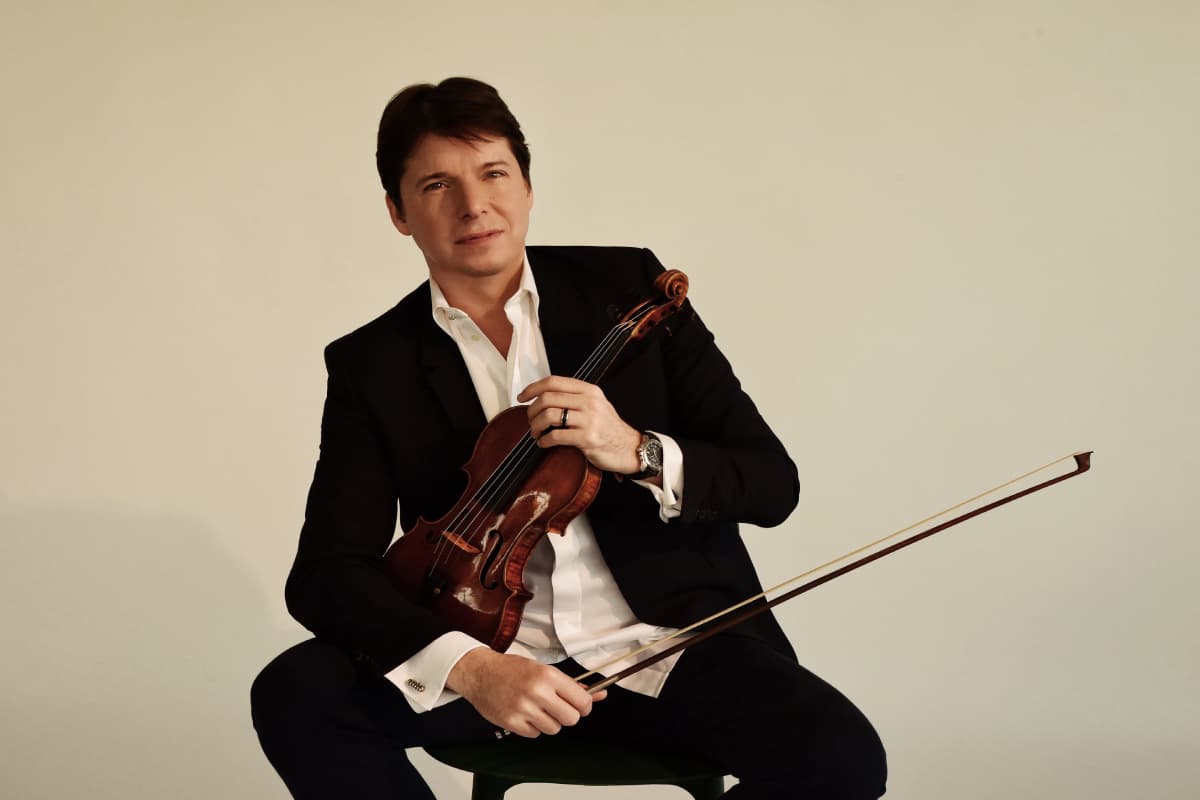 A man sitting down holding his violin.
