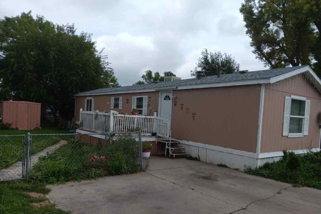 peach colored mobile home with fence in front