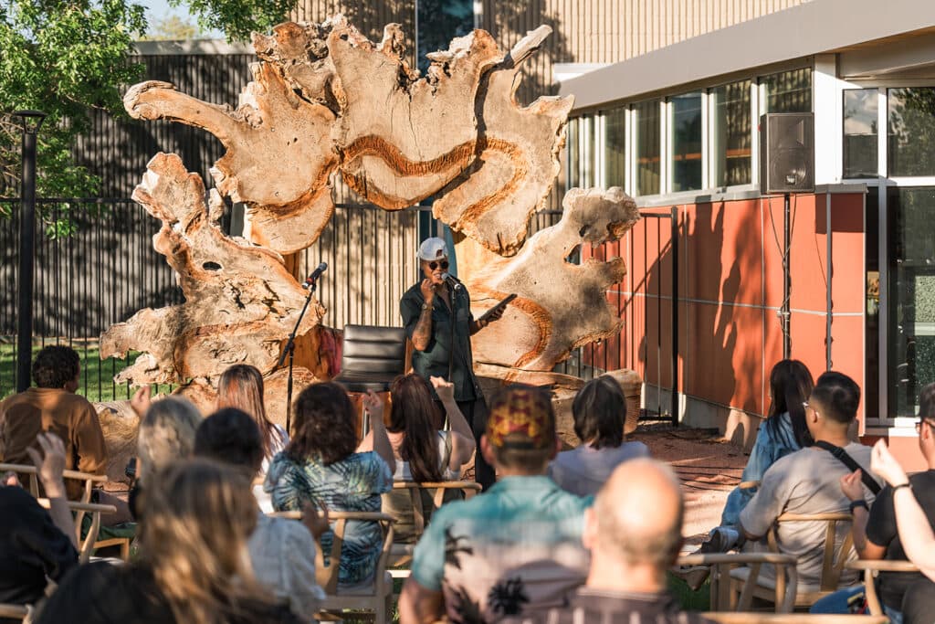 Kerrie Joy stands on an outdoor stage, addressing an audience.